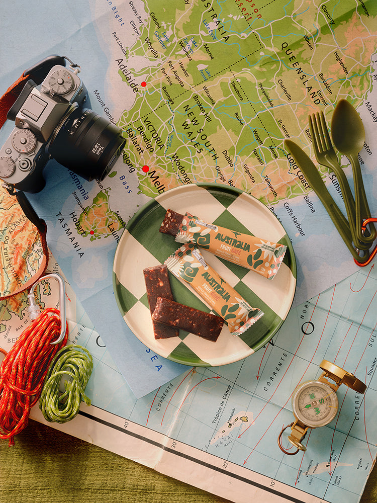 Barras AUSTRALIA sobre um mapa de viagem, ao lado de mochila e acessórios.