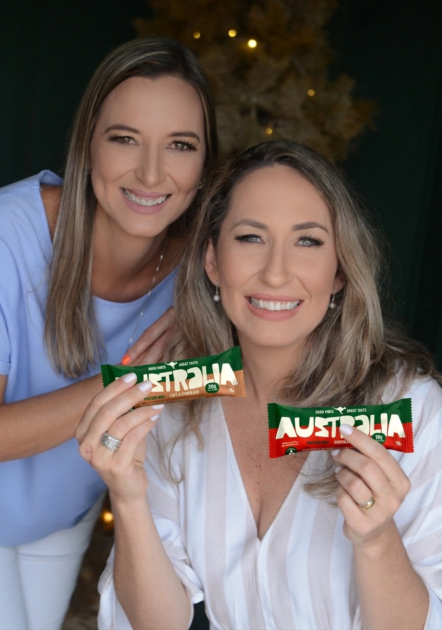 Raquel e Sabrina, irmãs e fundadoras da AUSTRALIA, segurando as barras de proteína na cozinha