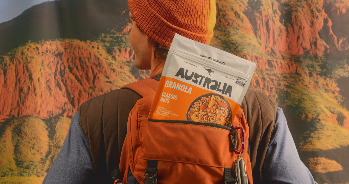 Pessoa com pouch Granola Chocolate AUSTRALIA em cenário rochoso.
