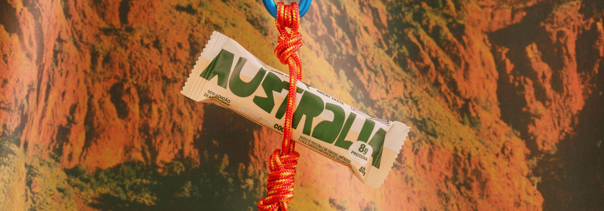 Barra Protein Slim AUSTRALIA junto a cordas sobre superfície rochosa.