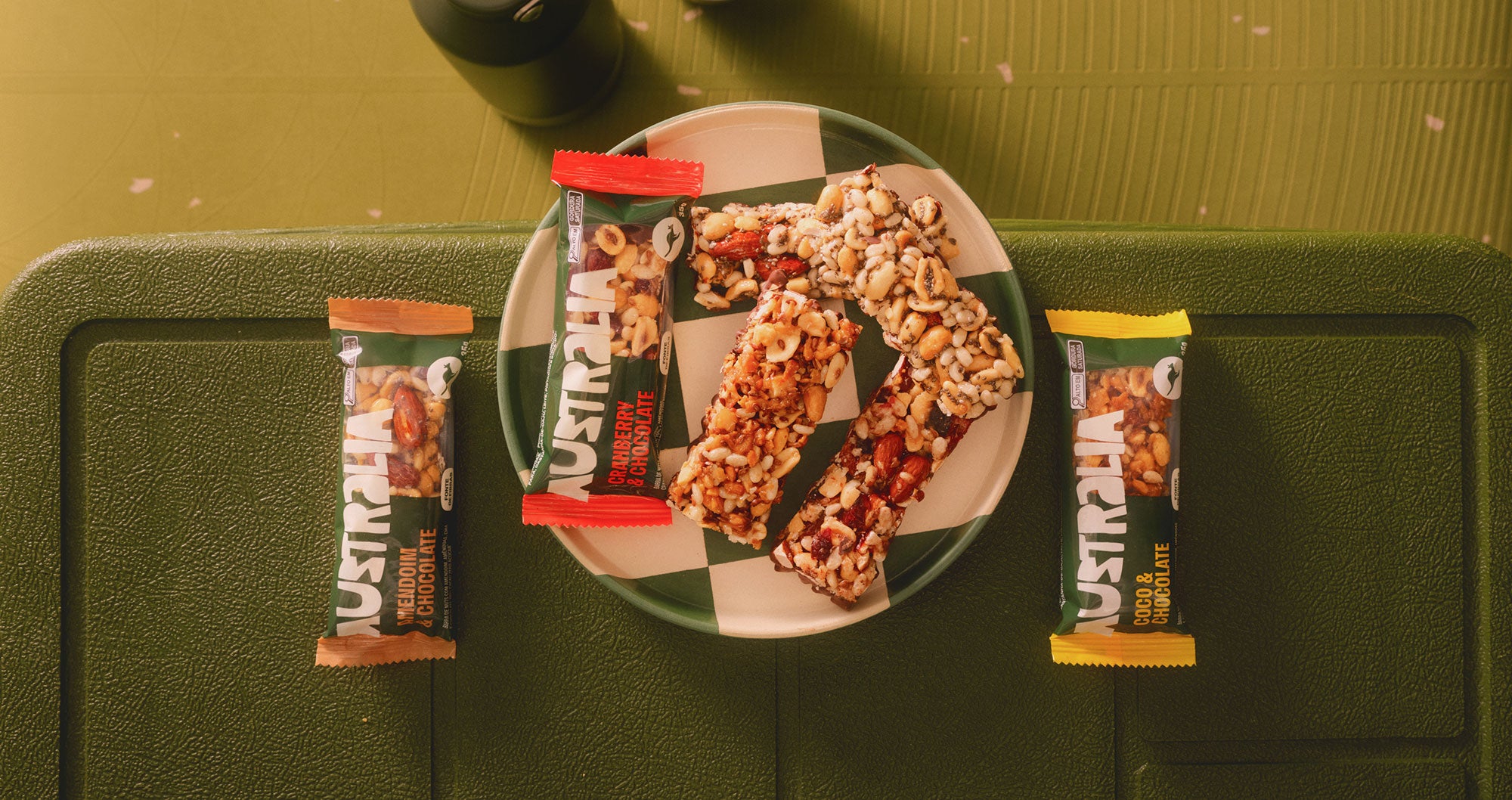 Barras Nuts AUSTRALIA com castanhas e chocolate em composição editorial.