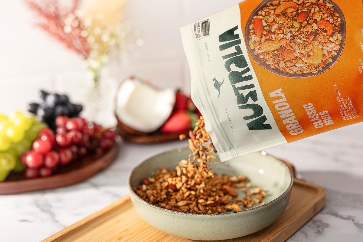 Granola Classic Nuts sendo servida do pacote em uma tigela, com frutas ao lado.