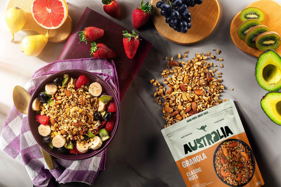 Uma mulher despeja granola de um pote numa tigela, com um pacote de Granola Keto Original na bancada.