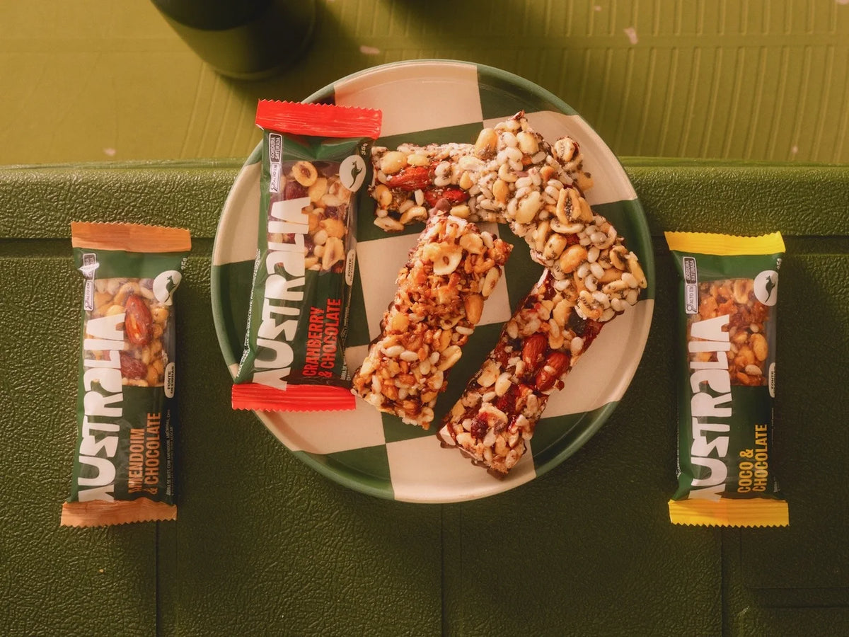 Barras Nuts partidas num prato, entre as embalagens de Amendoim, Cranberry e Coco